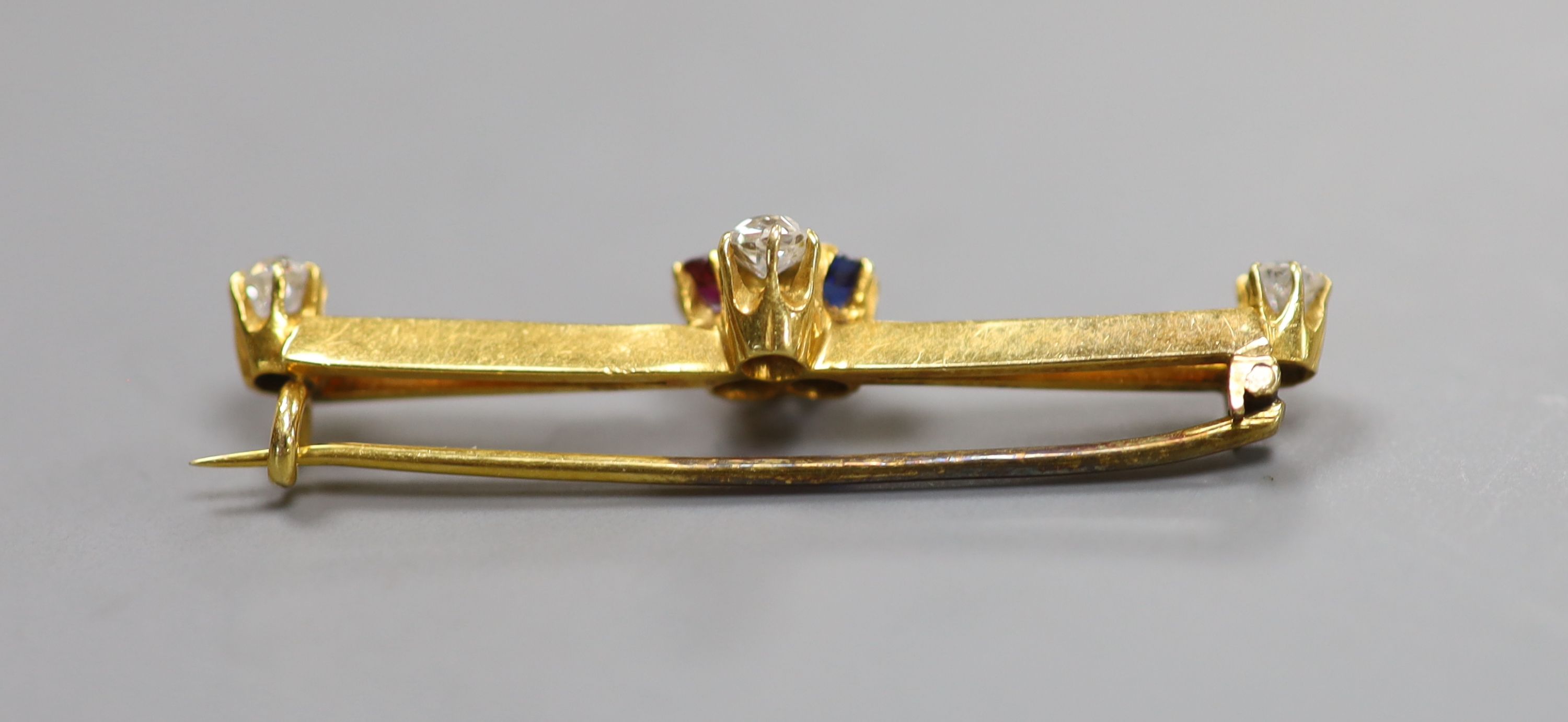 An Edwardian yellow metal, ruby, sapphire and diamond set clover bar brooch